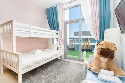 Kids' bedroom with white bunk bed, plush toys and pastel curtains