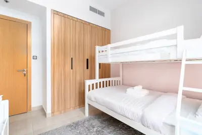 Second bedroom with triple bunk bed and wooden wardrobe