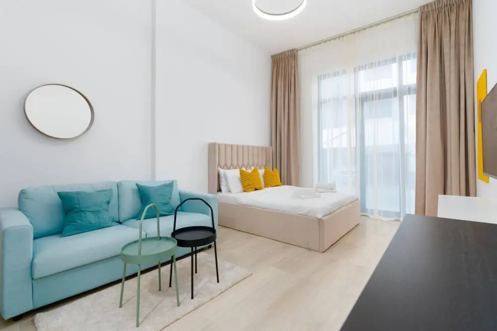 Studio living space with turquoise sofa, nesting tables and double bed