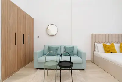Pastel blue loveseat between the wardrobe and upholstered bed