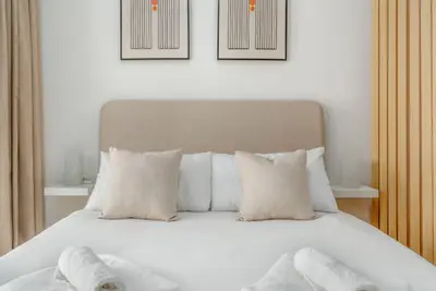 Close-up of the padded headboard, crisp linens and accent pillows