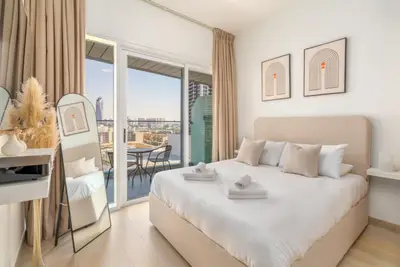 Comfy double bed beside a standing mirror and open balcony doors
