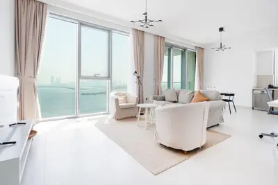 Sunlit living room with floor-to-ceiling windows facing the water