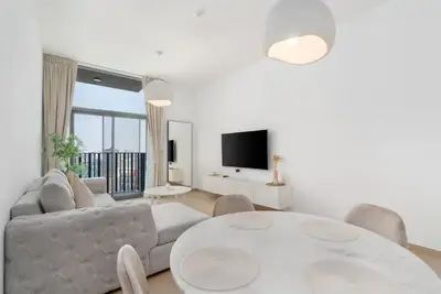 Bright living room with a round marble dining table and wall-mounted TV