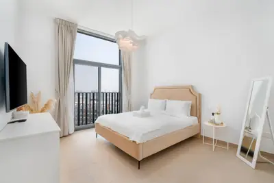 Bedroom with an upholstered beige bed, full-length mirror and sheer curtains