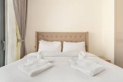 Neatly made bed with tufted headboard and folded towels