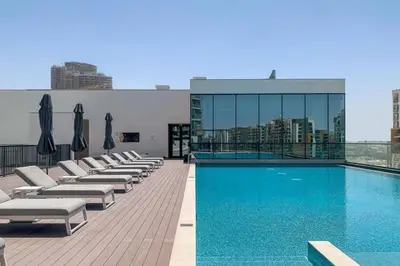 Rooftop pool with sun loungers and a glass-walled fitness pavilion