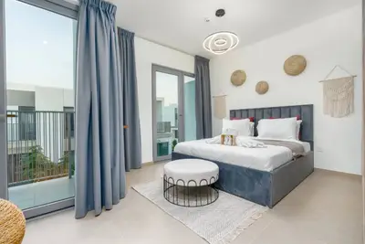 Master bedroom with velvet bed, round ottoman and balcony access