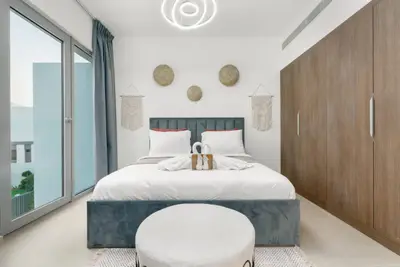 Grey upholstered bed framed by woven wall decor and a wide wardrobe