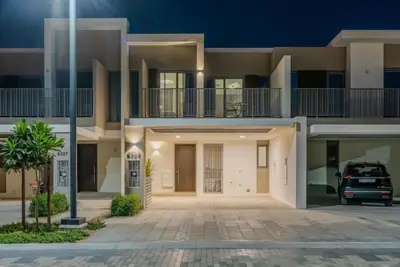 Modern two-storey townhouse exterior with covered parking at dusk
