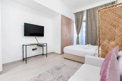 Wall-mounted TV facing the bed and sofa across the studio