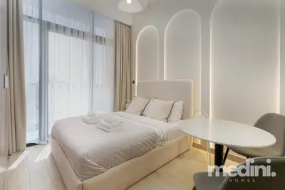 Bright studio sleeping area with arched lit wall panels and a round dining table