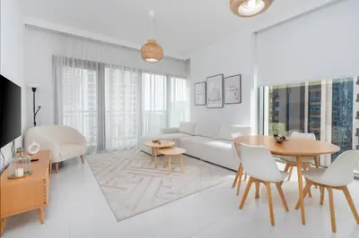 Open living room with sofa, round dining table and rattan pendant lights