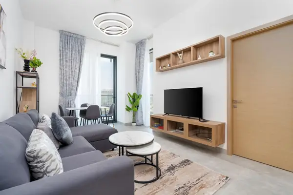 Living room with grey corner sofa, TV unit, and balcony beyond