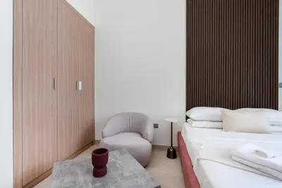 Bedroom side with built-in wardrobe, armchair, and partial bed view