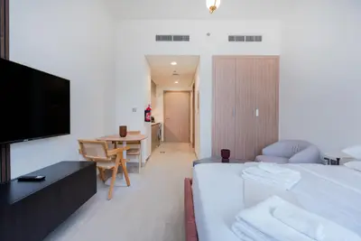 Studio layout with bed, dining table, TV unit, and wardrobe