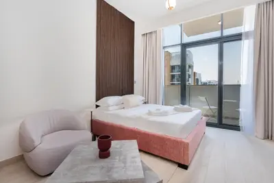Double bed with pink frame, armchair, and glass balcony door