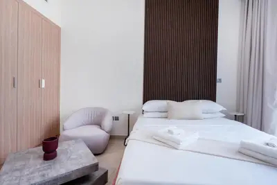 Bedroom corner with slatted wood wall, made bed, and accent chair