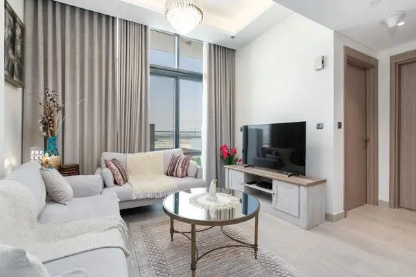 Living room with TV console, chandelier and soft grey curtains