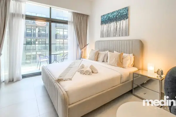 King bed by glass doors opening to a furnished balcony