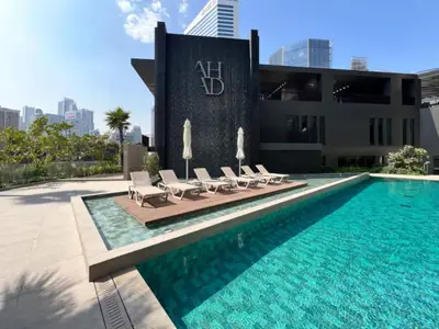 Resort-style building pool lined with sun loungers and parasols
