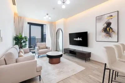Bright living room with beige sofas, wall-mounted TV and balcony access