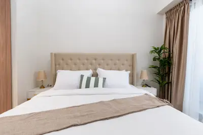 Queen bed with tufted headboard flanked by bedside lamps and greenery