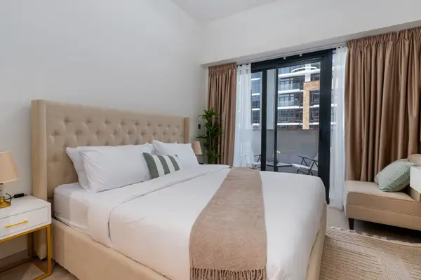 Bed beside floor-to-ceiling windows opening onto the balcony