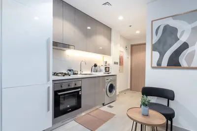 Sleek grey kitchenette with oven, washer and a cozy dining nook