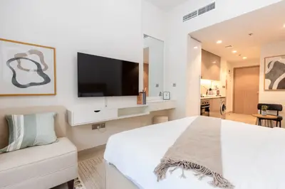 Studio layout showing the bed, wall TV and kitchenette beyond
