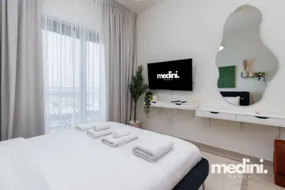 Another angle of the bed with fresh towels, facing TV and wavy mirror
