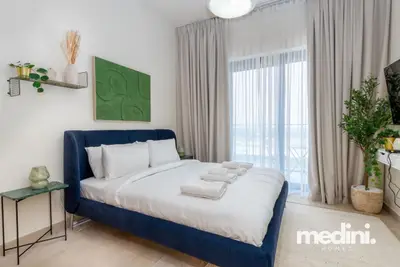 The sleeping area framed by long curtains and a leafy plant