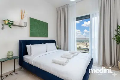 Navy upholstered bed dressed in white linen beneath green wall art