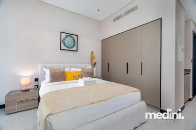 The bed seen beside built-in wardrobes and soft beige styling