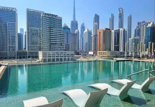Rooftop pool with white loungers facing the Dubai skyline