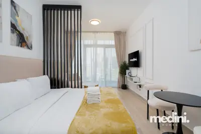 Another angle of the bed with mustard throw, facing the wall TV and bistro table