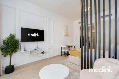Living corner with wall-mounted TV, potted plant and round coffee table