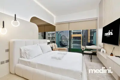 Designer studio with plush white bed, ring lights and wall TV