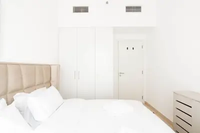 Bedroom with padded headboard, built-in wardrobe and wooden dresser