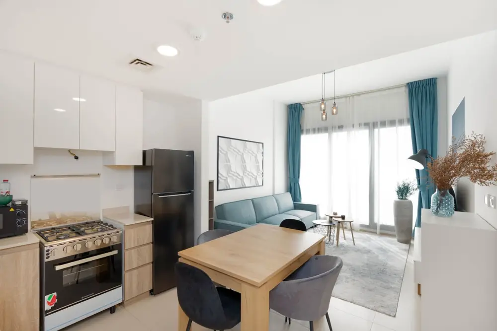 Open plan living space with kitchen, dining table and blue sofa