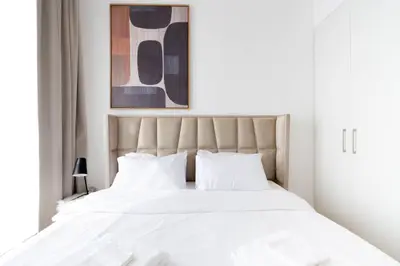 Plush tufted headboard and abstract canvas above the crisp white bed