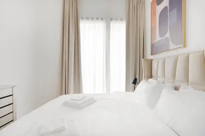 White bedding topped with folded towels beneath abstract wall art
