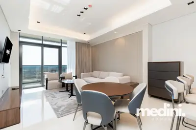 Open living and dining area with round table, sofa and wall-mounted TV