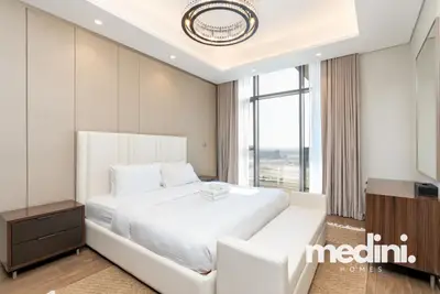 Bedroom with upholstered bed, ring chandelier and floor-to-ceiling window