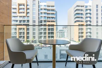 Two armchairs and a bistro table on the balcony facing the community