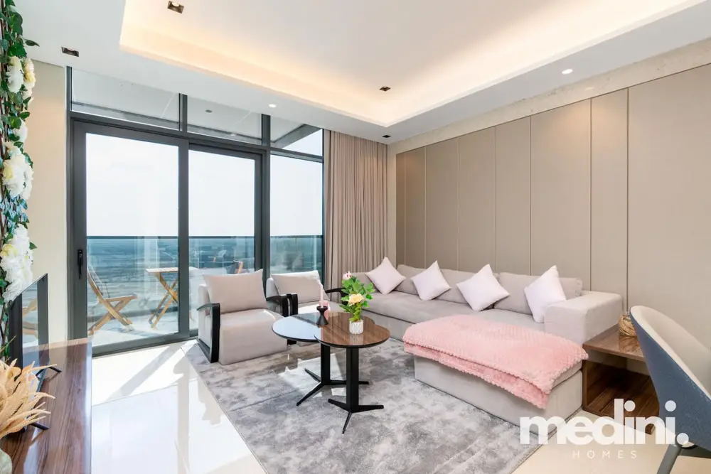 Living room with beige sectional, pink accents and floor-to-ceiling glass