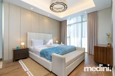 Bedroom with teal throw, ring chandelier and warm wooden flooring
