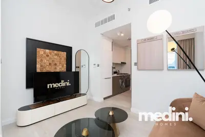 The lounge corner with TV, arch mirror and kitchenette beyond
