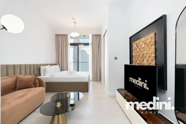 Studio living space with plush bed, curved sofa and mounted TV