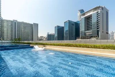 Rooftop swimming pool with clear blue water and city high-rises in the background